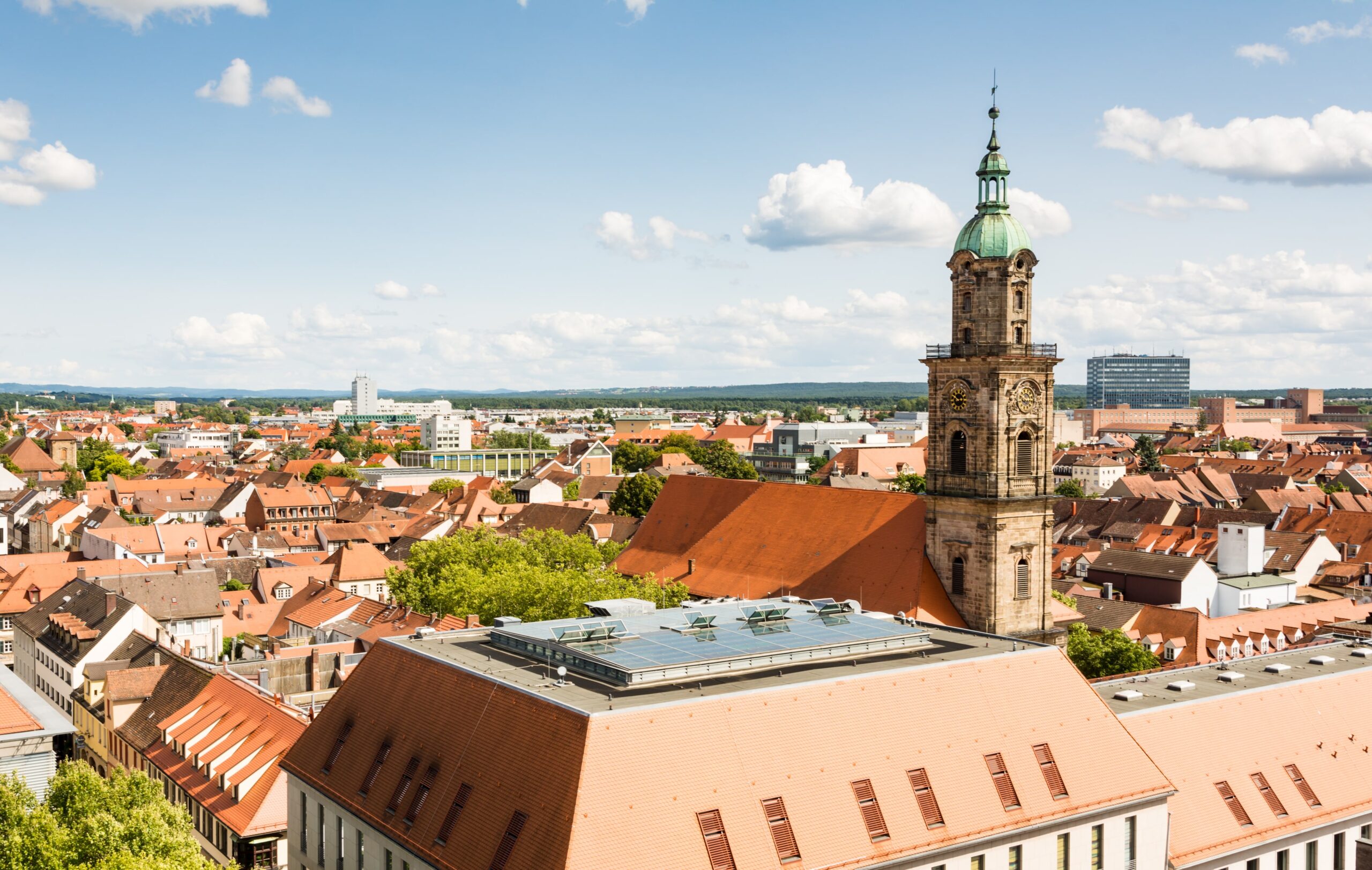 Stadtansicht mit historischen Gebäuden und Solaranlagen; Fokus auf den Turm und das Dach. Climate Energy.