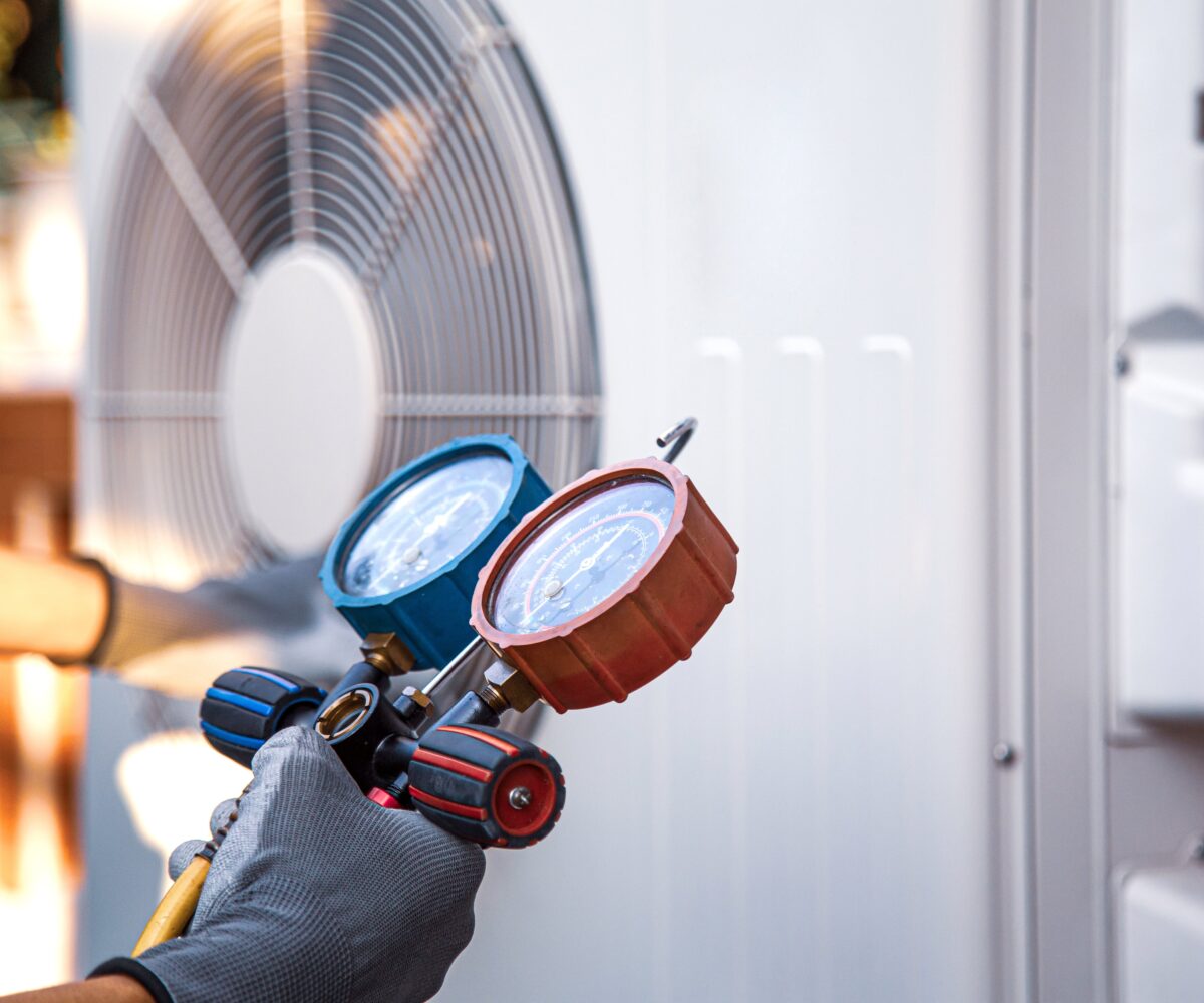 Ein Techniker &uuml;berpr&uuml;ft mit Druckmanometern eine Klimaanlage. Fokus auf Klimaanlagenwartung. Climate Energy.