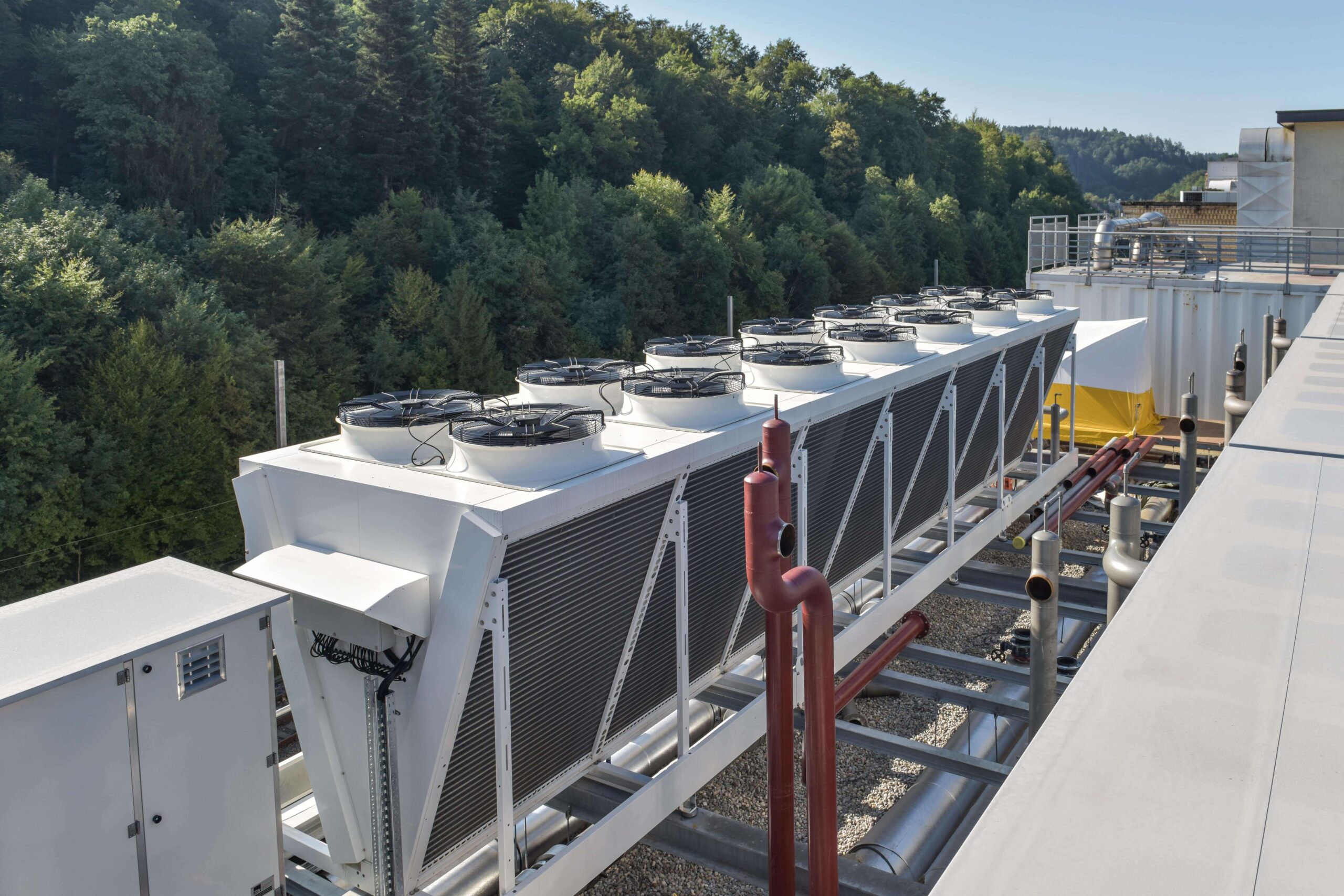 Klimaanlage auf dem Dach mit mehreren Kühltürmen, umgeben von Wald. Klimaanlage Energie.
