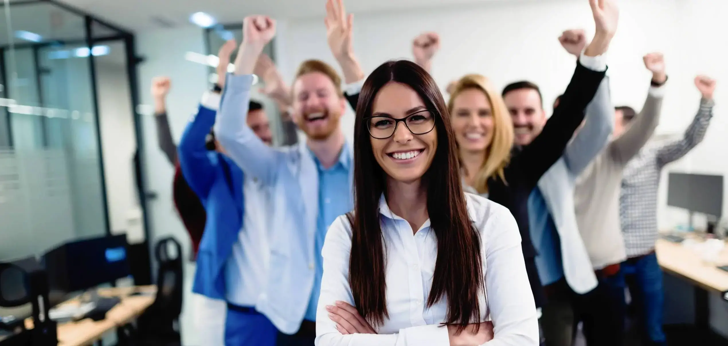 Lächelnde Mitarbeiterin im Vordergrund mit jubelndem Team im Hintergrund – Arbeiten bei Climate Energy GmbH