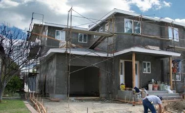 Neubau eines Hauses mit Gerüst, Arbeiter bei der Fertigstellung, Fokus auf nachhaltige Bauweise. Climate Energy.