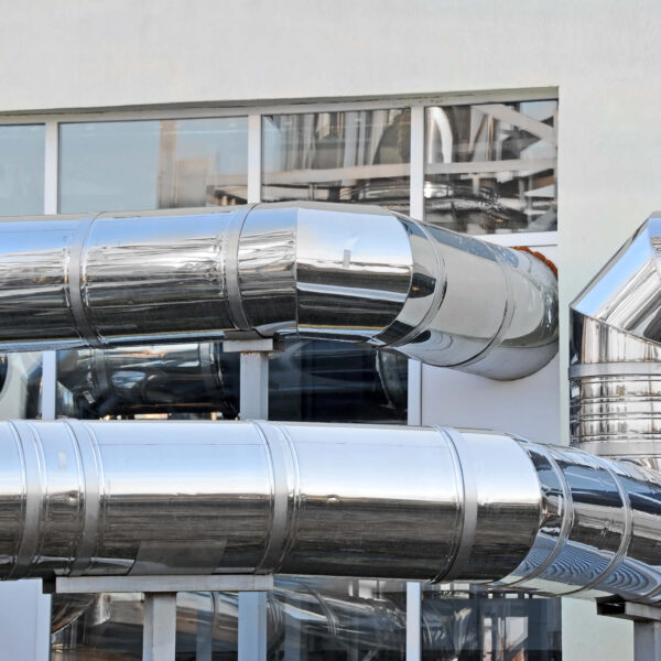 Glänzende Rohrleitungen an einem Gebäude, Symbol für moderne Energietechnologie. Climate Energy.