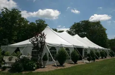 Zelt mit spitzen Dächern, umgeben von Bäumen und Sträuchern, bei sonnigem Wetter. Climate Energy.