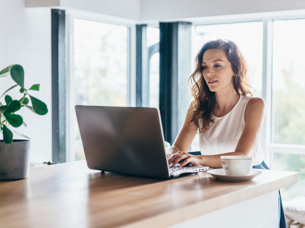 Frau arbeitet am Laptop im hellen Raum – komfortables Arbeiten und Klimaenergie.